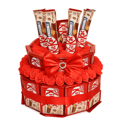 Professionele productfoto van een twee-laagse KitKat cadeautaart met rode kunstroosjes en een luxe rode satijnen strik. Geen ac