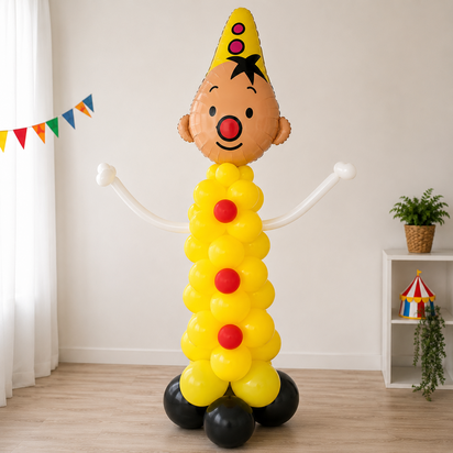 Gele ballonpilaar met rode accenten en een grote Bumba folieballon bovenaan. De ballonpilaar staat op een stevige zwarte ballon